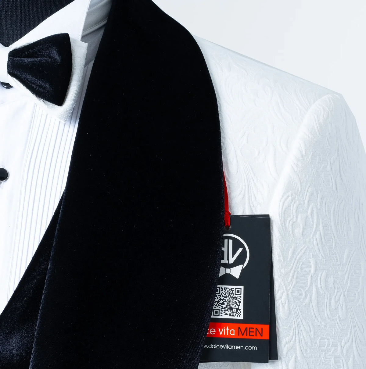 Close-up of a Gianni Collection white textured tuxedo jacket featuring a plush black velvet shawl lapel and matching velvet bow tie by Dolce Vesta.