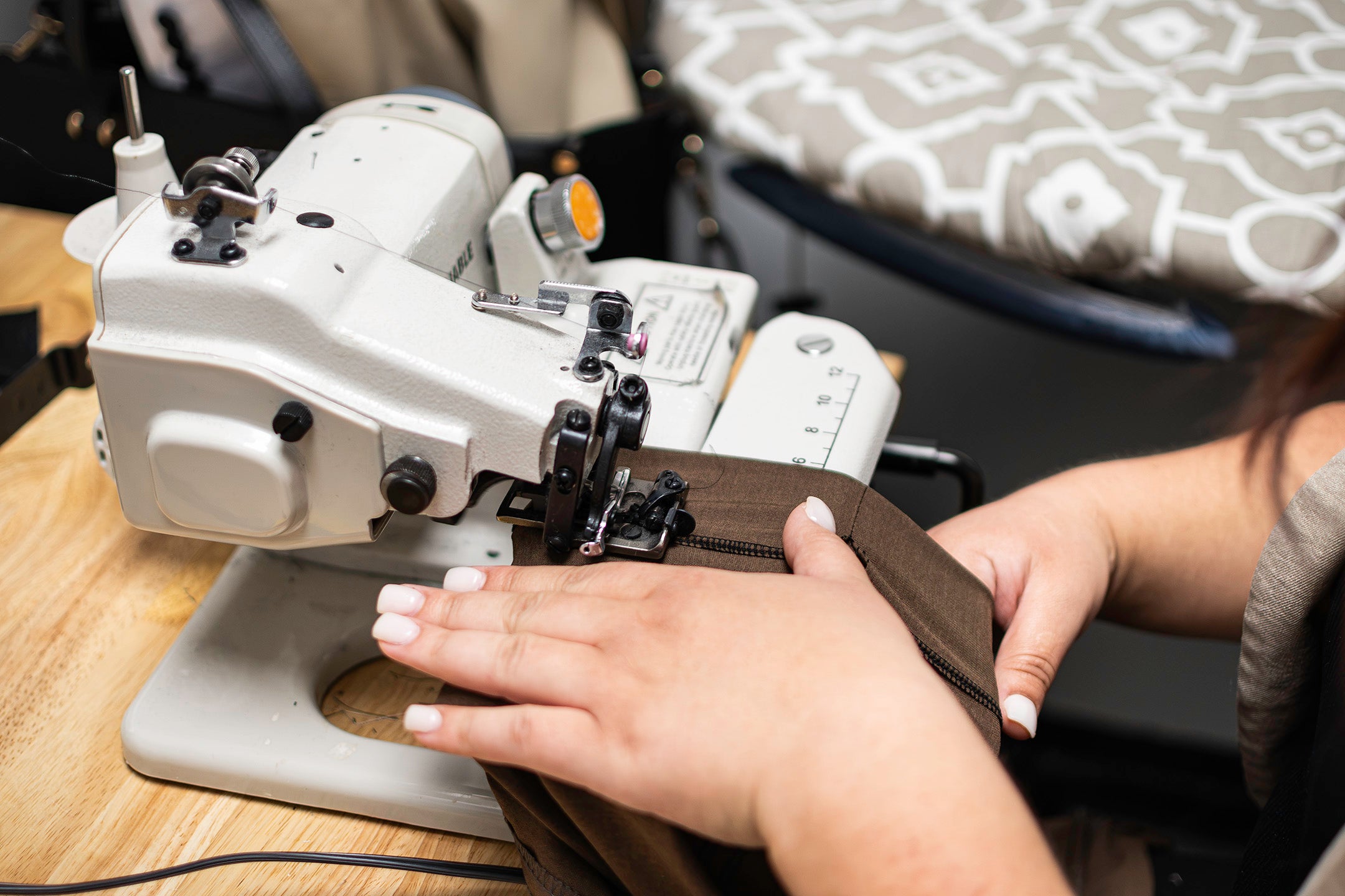 Precision hands carefully altering a garment on a blind hem sewing machine, highlighting Dolce Vesta's custom fit and quality craftsmanship.